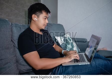 Asian Businessman Using Wireless Earphones And Using Computer Notebook Working From Home.he Is Prepa