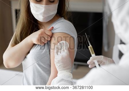 Doctor In Personal Protective Suit Or Ppe Inject Vaccine Shot To Stimulating Immunity Of Woman Patie