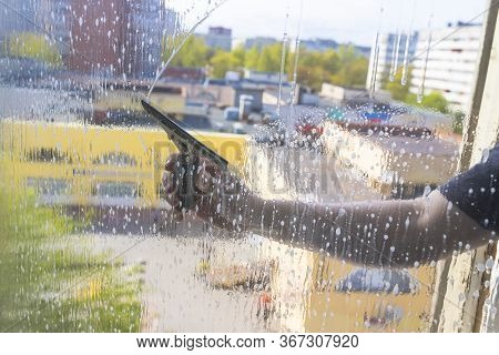 Rubber Squeegee In Male Hand Cleans A Soaped Window