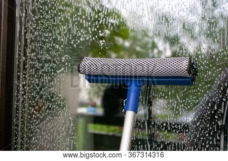 Cleaning Glass Of Window Using A Squilgee.