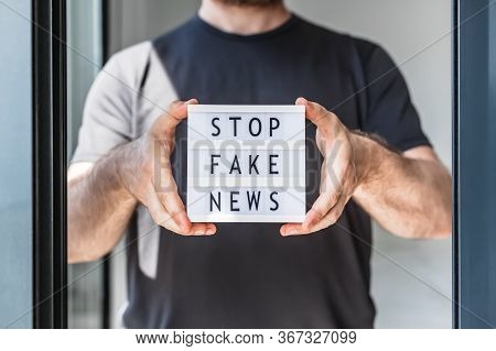 Fake News Infodemics During Covid-19 Pandemic Concept. Man Hands Holding Lightbox With Text Stop Fak