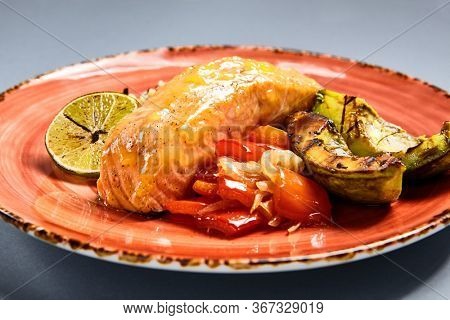 Salmon piece with rice and lime side view. Fish with garnish. Fancy restaurant dish close up. Luxury seafood meal on ceramic peach craft plate. Food presentation art. Delicious lunch course