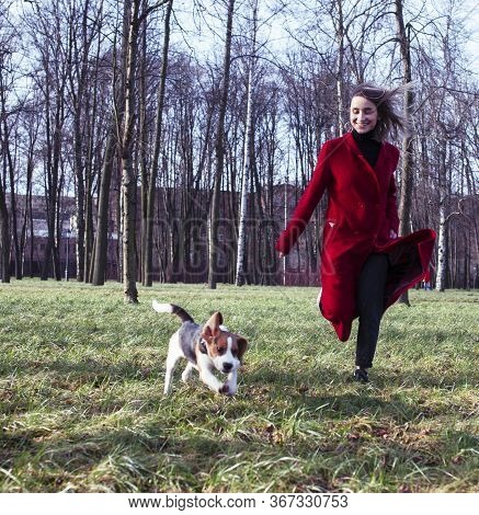 Pretty Young Girl In Redd Coat Playing With Dog Outside In Green Park, Lifestyle People Concept