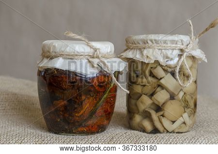 Jars Of Canned Food On Burlap. Two Glass Jars With Canned Mushrooms And Sun-dried Tomatoes. Ingredie