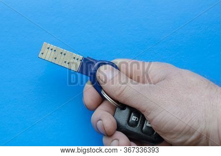 Chipped Door Key With A Remote Control In Hand. A Man Demonstrates An Innovative Key With A Unique S