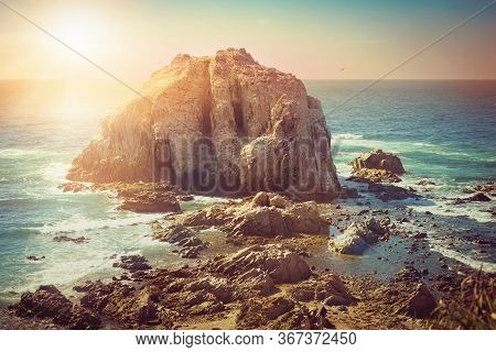 Rocky Island With Birds Near Coastilne Of Pacific Ocean In Chile At Sunset