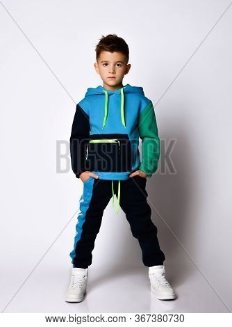 Serious Boy In Stylish Cotton Jym Suit Standing With Legs Apart Keeping Hands In Pockets. Children A