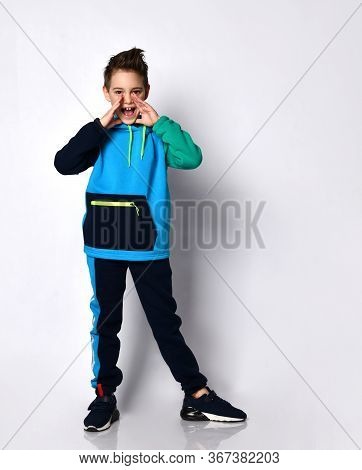 Cute Little School Boy With A Stylish Haircut In A Bright Cotton Tracksuit Shouting Calling Someone.
