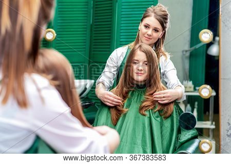 Hairdresser Makes Hairstyle For Beautiful Woman While Looking In The Mirror Reflaction At The Beauty