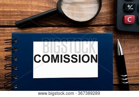 Word Comission Written On A Notebook With Calculator And Magnifying Glass On Wooden Backround.