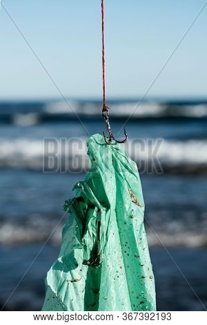 closeup of a used green plastic bag in a fish hook, freshly fished in the ocean