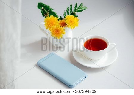 Morning Tea With Light Blue Mobile Phone, Bouquet Of Yellow Spring Dandelion Flowers. Beautifully St
