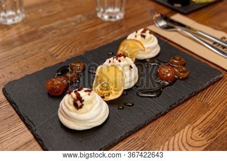 Meringue dessert with orange chips and leechee jam on restaurant table