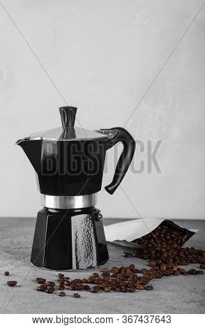 Black Geyser Coffee Maker On A Stone Table. Coffee Beans Are Scattered Nearby.