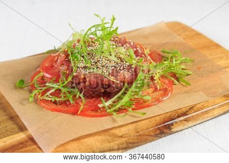 Close-up Of Tuna Tartare With Bread Slices Over Black Wooden Background, Studio Shot