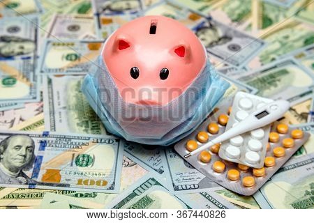 Piggy Bank In A Mask On A Background Of American Currency.the Concept Of Coronavrius Epidemic