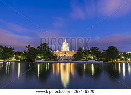 The United States Capitol Building At Sunset Wirh Reflection In Water.
