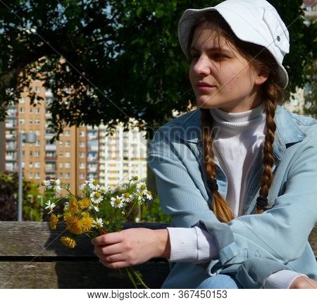 Beautiful Girl In A Denim Suit And White Panama Hat Sits On A Bench With A Bouquet Of Dandelions In 