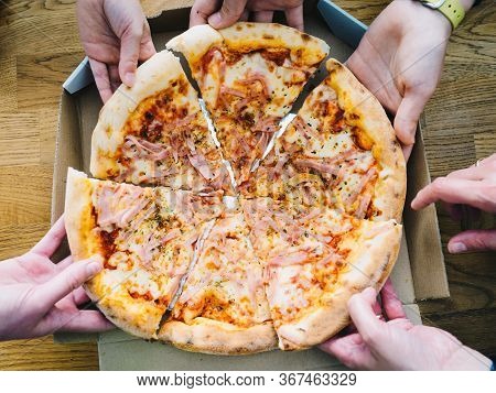 Hands Of Young People Taking Pizza Slices From Delivery Cardboard Box Dining Together, Friends Shari