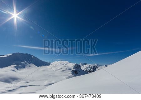 Sun And Blue Sky Over Sandhubel Mountain Near Swiss Arosa In Winter Landscape