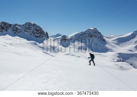 Women With Snowshoes Walking In  Snowy Winter Landscape In Schanfigg Near Arosa With Blue Sky