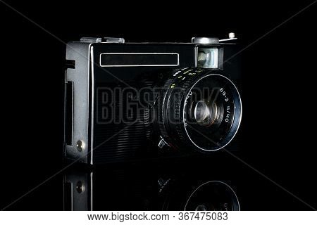 One Whole Dark Vintage Camera Isolated On Black Glass