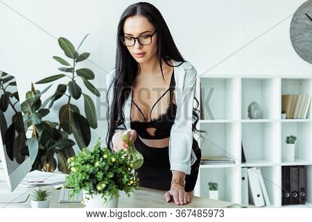 Focus Of Sensual Secretary In Bra Spraying Plant On Working Table