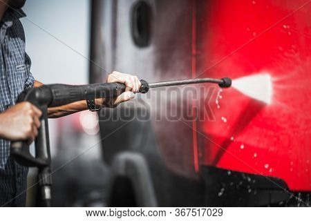 Close Up Of Man Spraying Exterior Of Red Semi Truck Using Self Service Equipment At Car Wash.