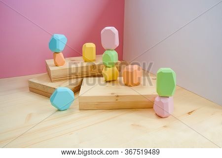 Abstract Figures From Elements Of Wooden Tumi Ishi Pastel Colors On A Wooden Podium On A Paper Backg