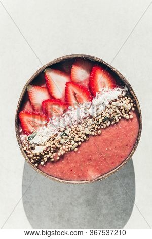 Pink Smoothie From Banana And Strawberries With Pieces Of Strawberries, Granola And Coconut Shreds O
