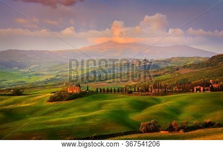Amazing colorful sunset in Tuscany. Picturesque agrotourism and typical curved road with cypress, Crete Senesi rural landscape in Tuscany, Italy, Europe
