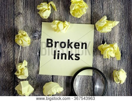 Broken Links - Text On Yellow Note Sheets On A Dark Wooden Background With Crumpled Sheets And A Mag