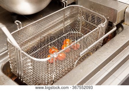 Friture cooker in restaurant kitchen, cherry tomatoes about to being deep fried