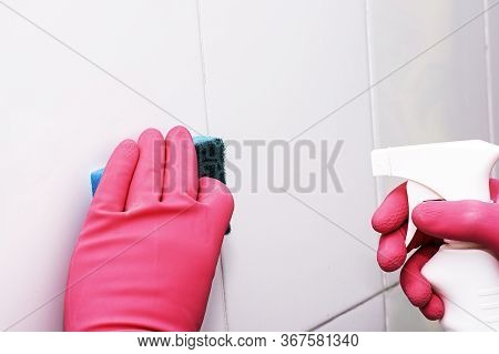 Bman In Rubber Household Gloves With A Sponge And Spray Washes A White Tiled Wall