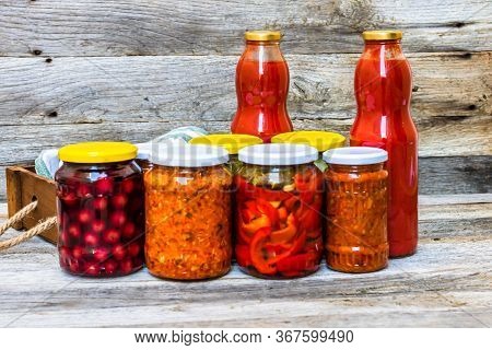 Jars With Variety Of Canned Vegetables And Fruits, Jars With Zacusca And Bottles With Tomatoes Sauce