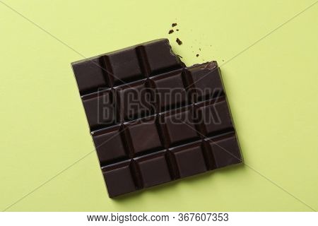 Tasty Dark Chocolate Bar With Bite Mark On Yellow Background, Top View