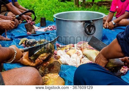 People Cutting Raw Meat Together In Village.butchers Cutting Raw Meat