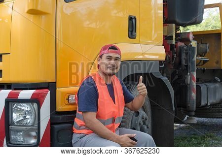 An Asian Man Was Smiling Happily At The Yellow Truck. He Has A Career As A Transport Driver. The Tra