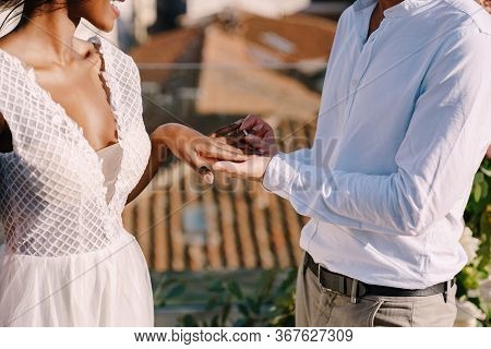 Multiracial Wedding Couple - African-american Bride And Caucasian Groom. Groom Puts A Ring On Brides