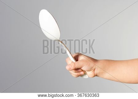 Child Hand Holding White Spoon In Right Hand In Not Right Way On The White Background