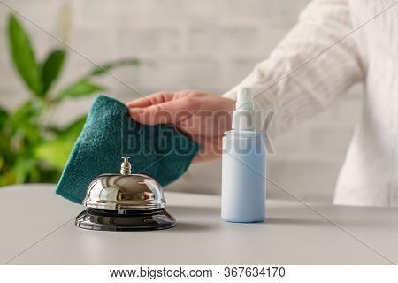 Hand Of Woman Cleaning Ringing Bell On Reception Desk. Disinfection Spray, Small Towel. Protection F