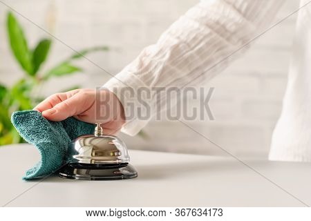 Hand Of Woman Cleaning Ringing Bell On Reception Desk. Disinfection Spray, Small Towel. Protection F