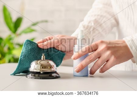Hand Of Woman Cleaning Ringing Bell On Reception Desk. Disinfection Spray, Small Towel. Protection F