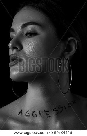 Black And White Dramatic Portrait Of A Young Woman With The Inscription Aggressive On A Black Backgr