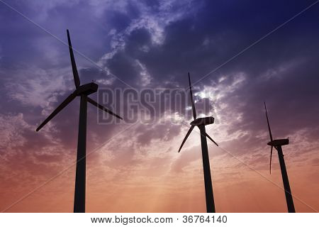 Aerogenerator mulini a vento in energia elettrica cielo drammatico tramonto verde