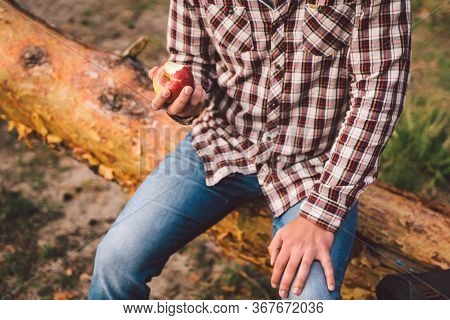 Man Eating An Apple On Hiking Trip In Forest. Hiker Taking Break While Trekking In Wilderness. Male 