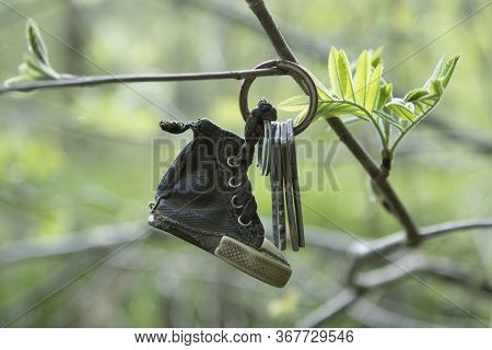 Lost Keys To The Apartment With A Old Keychain, Trinket In The Form Of A Boot Hang On A Tree Branch 