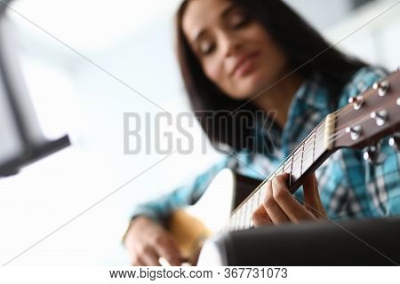 Young Woman Picks Up Guitar Chords At Home Couch. Quality Distance Education During Quarantine. Tale