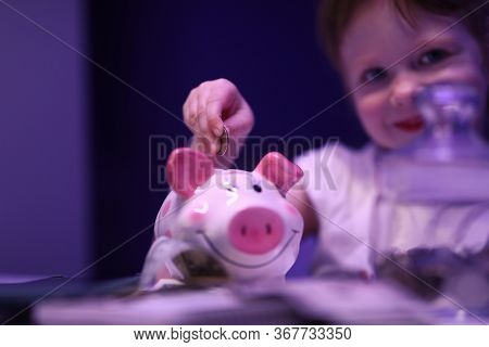Portrait Of Lovely Child Putting Coin In Pink Piggy Bank. Smiling Charming Girl Saving Up Money For 