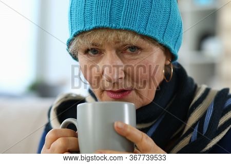 Elderly Woman Feels Sick And Drinks Tea At Home. Lady In Knitted Hat Takes Cup Tea. Parents Do Not T